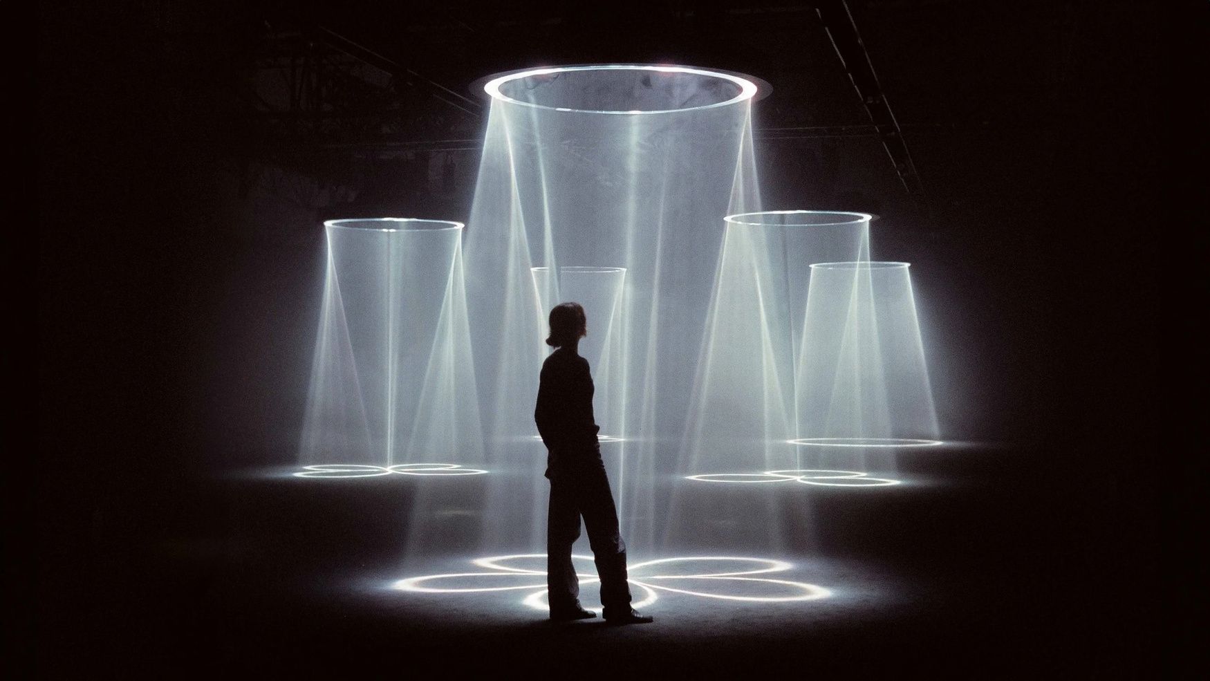 A figure standing among cones of light